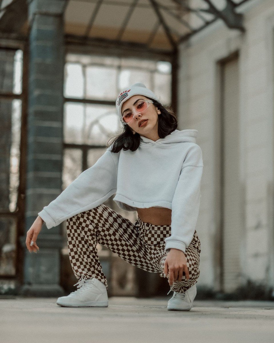 Model in a white cropped hoodie and checkered pants in a streetwear pose